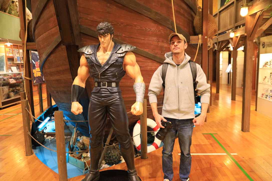 Guest posing with life-size Kenshiro statue from Fist of the North Star at Kaiyodo Hobby Museum