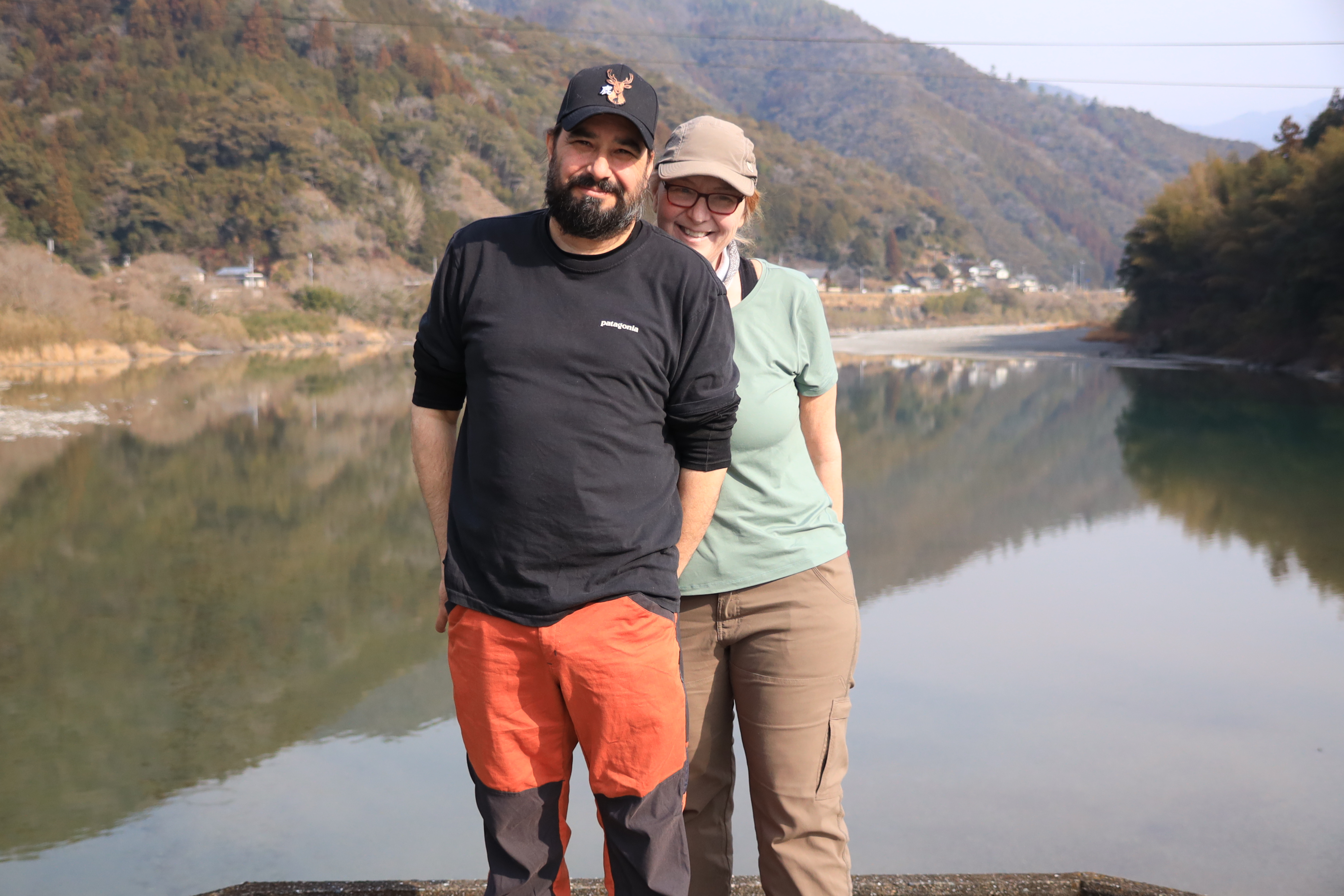 Couple posing by the Niyodo River with mountains reflected in crystal clear water