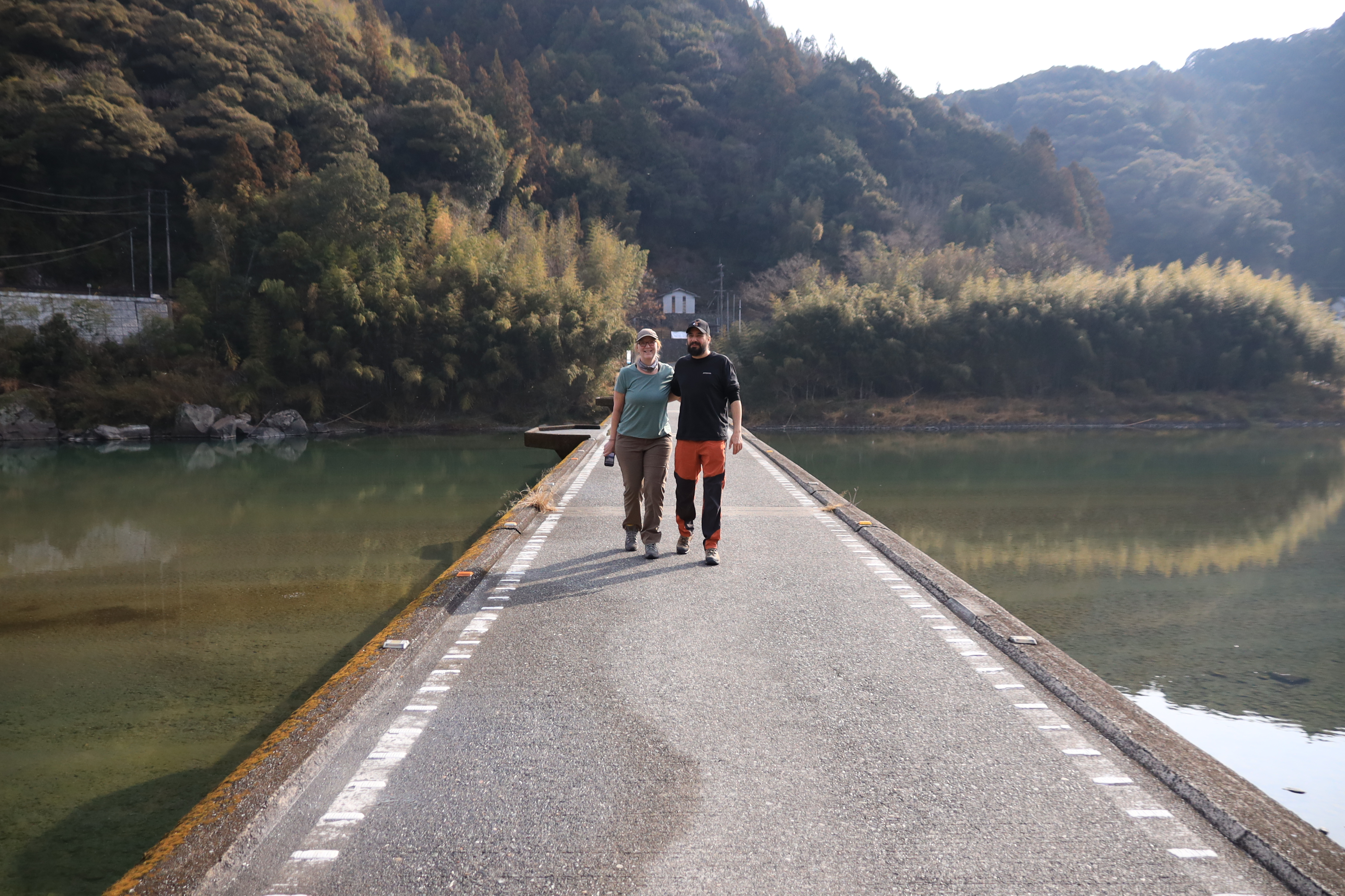 Couple walking on a scenic bridge over the Niyodo River surrounded by mountains