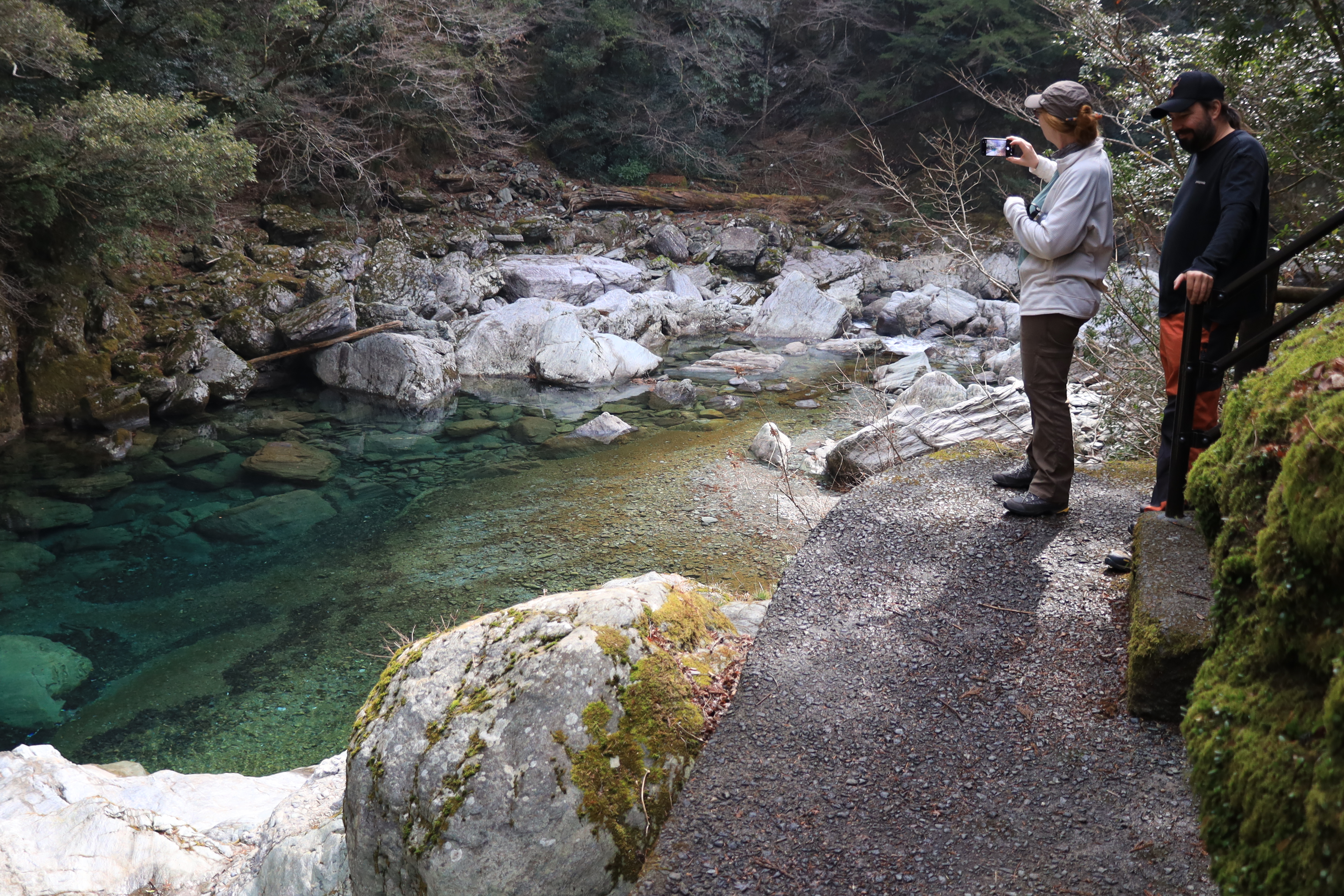Guests admiring the turquoise blue water of the Niyodo River with moss-covered rocks