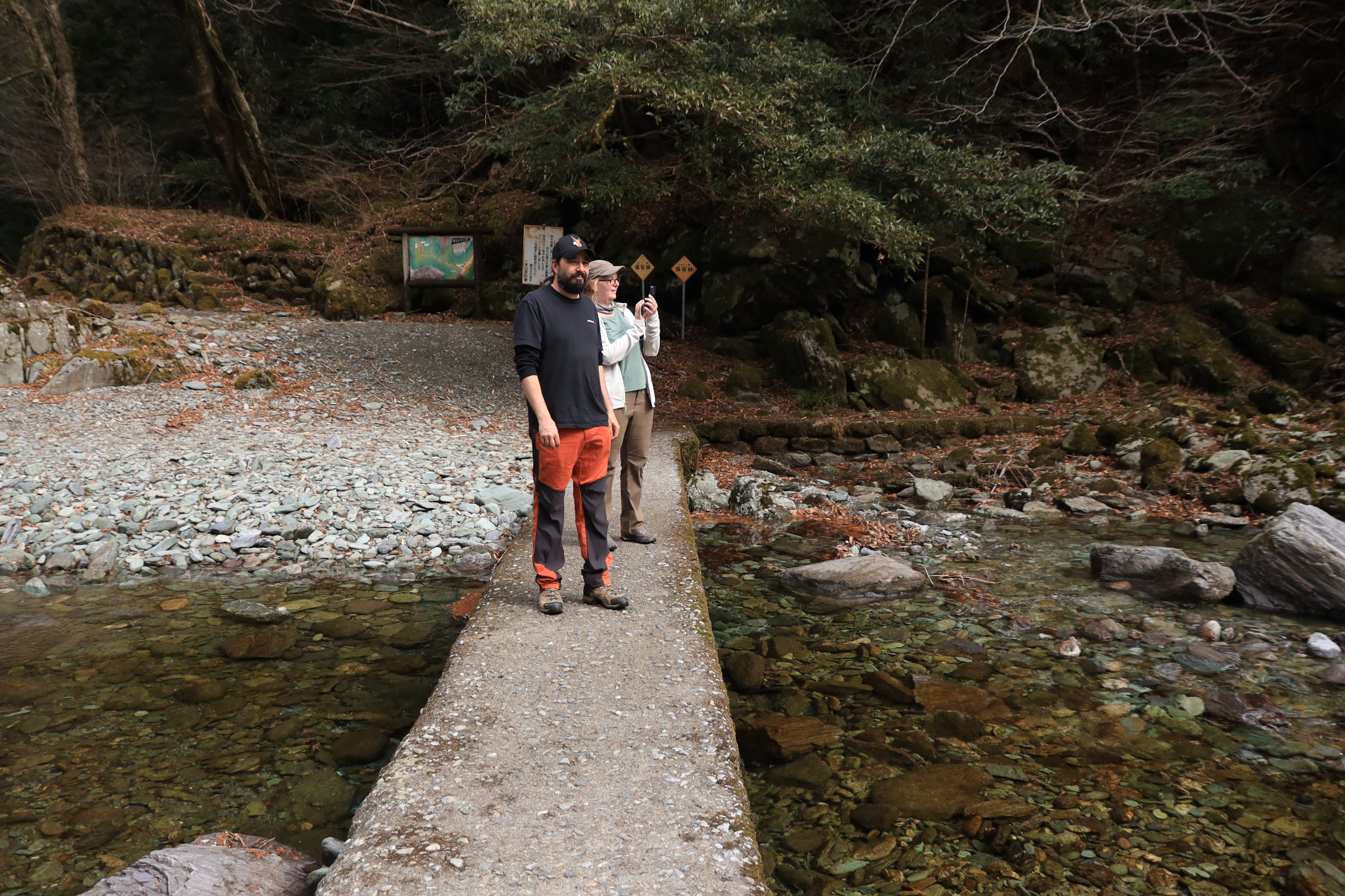 Guest sitting peacefully on a rock by the crystal clear stream taking photos