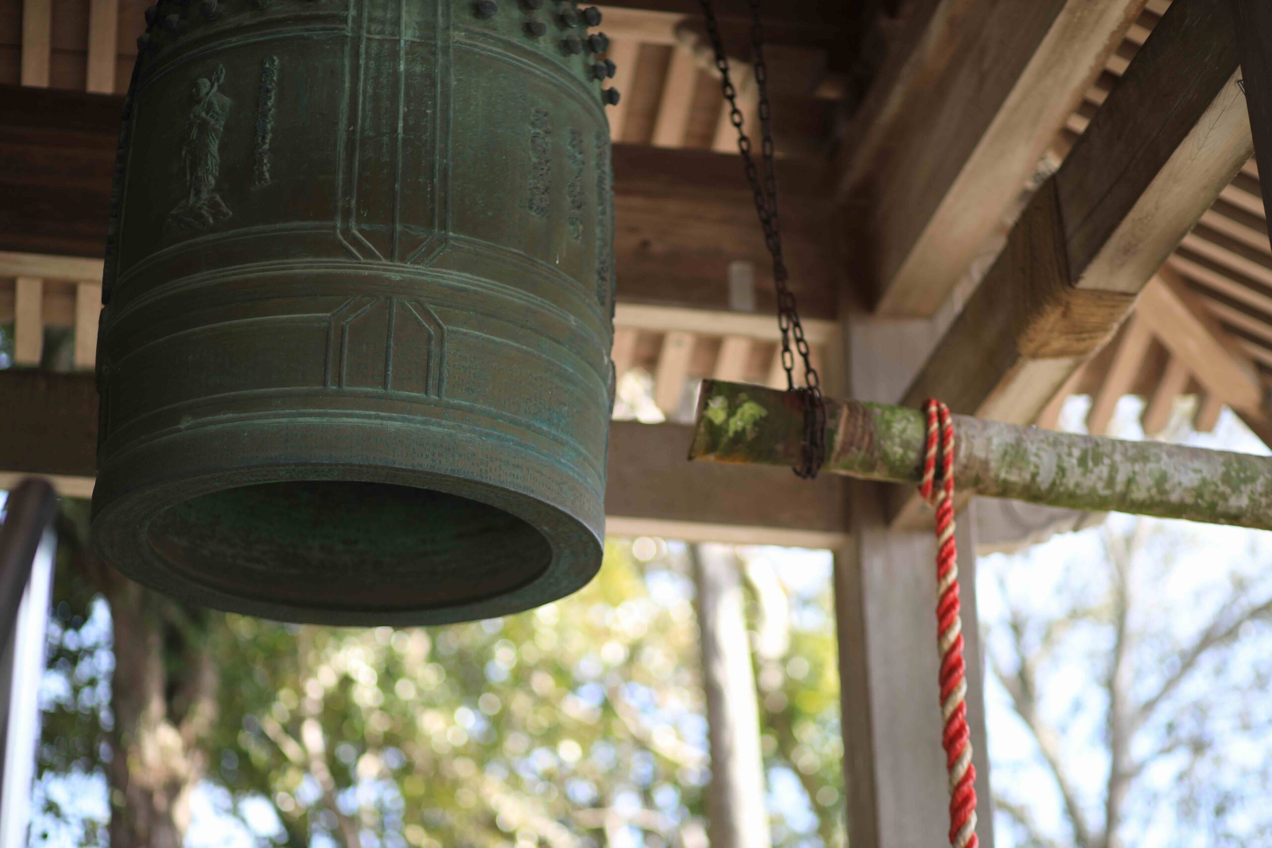Ancient bronze temple bell with red and white rope at Zenjibuji Temple