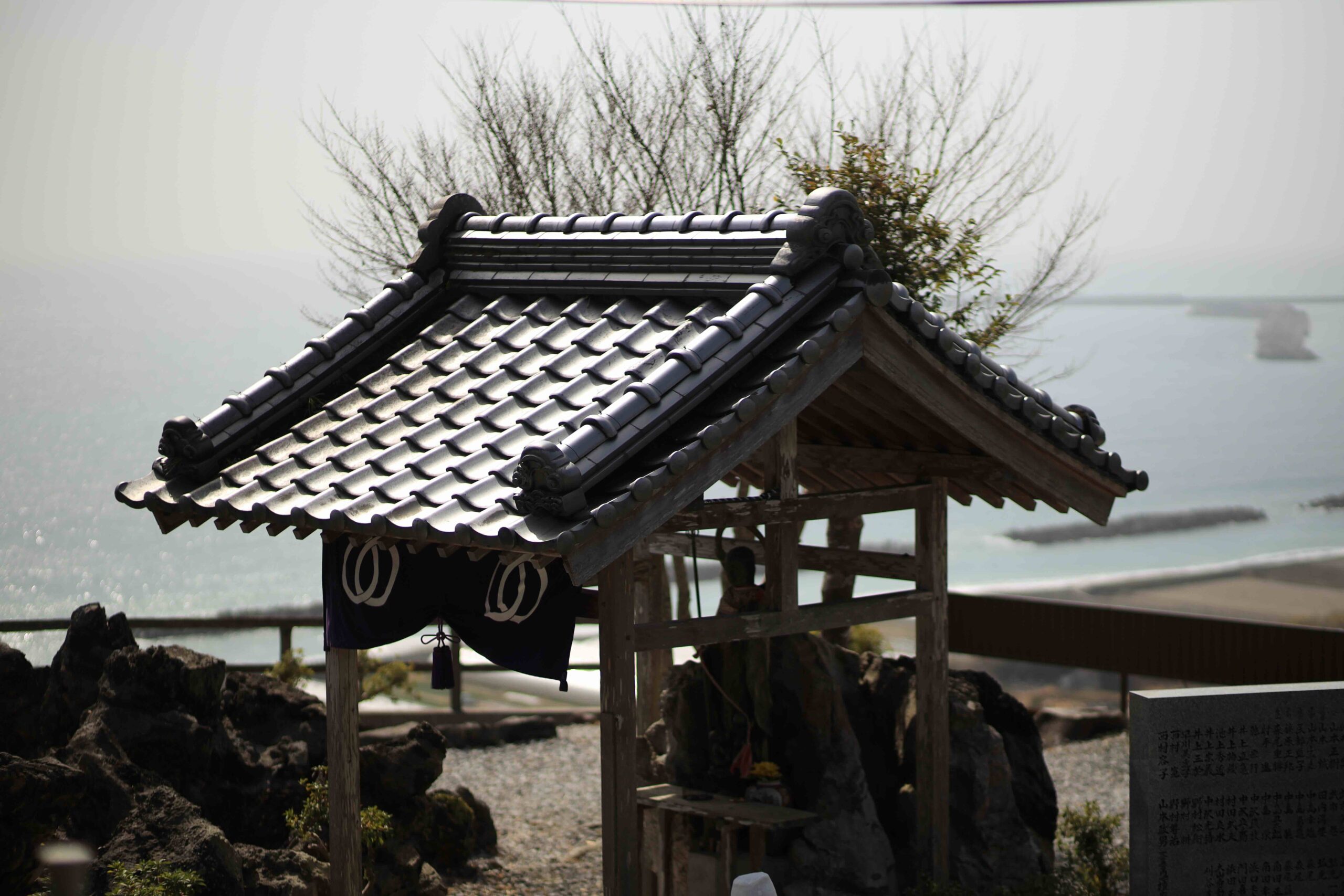 Stone Jizo statues with red bibs in dappled forest light on the Shikoku Pilgrimage