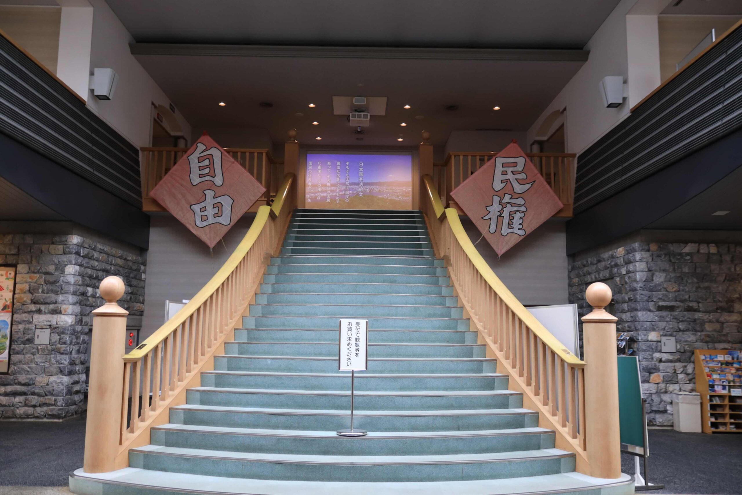 Inside the Jiyuminken Kinenkan with Freedom and Civil Rights banners above the staircase
