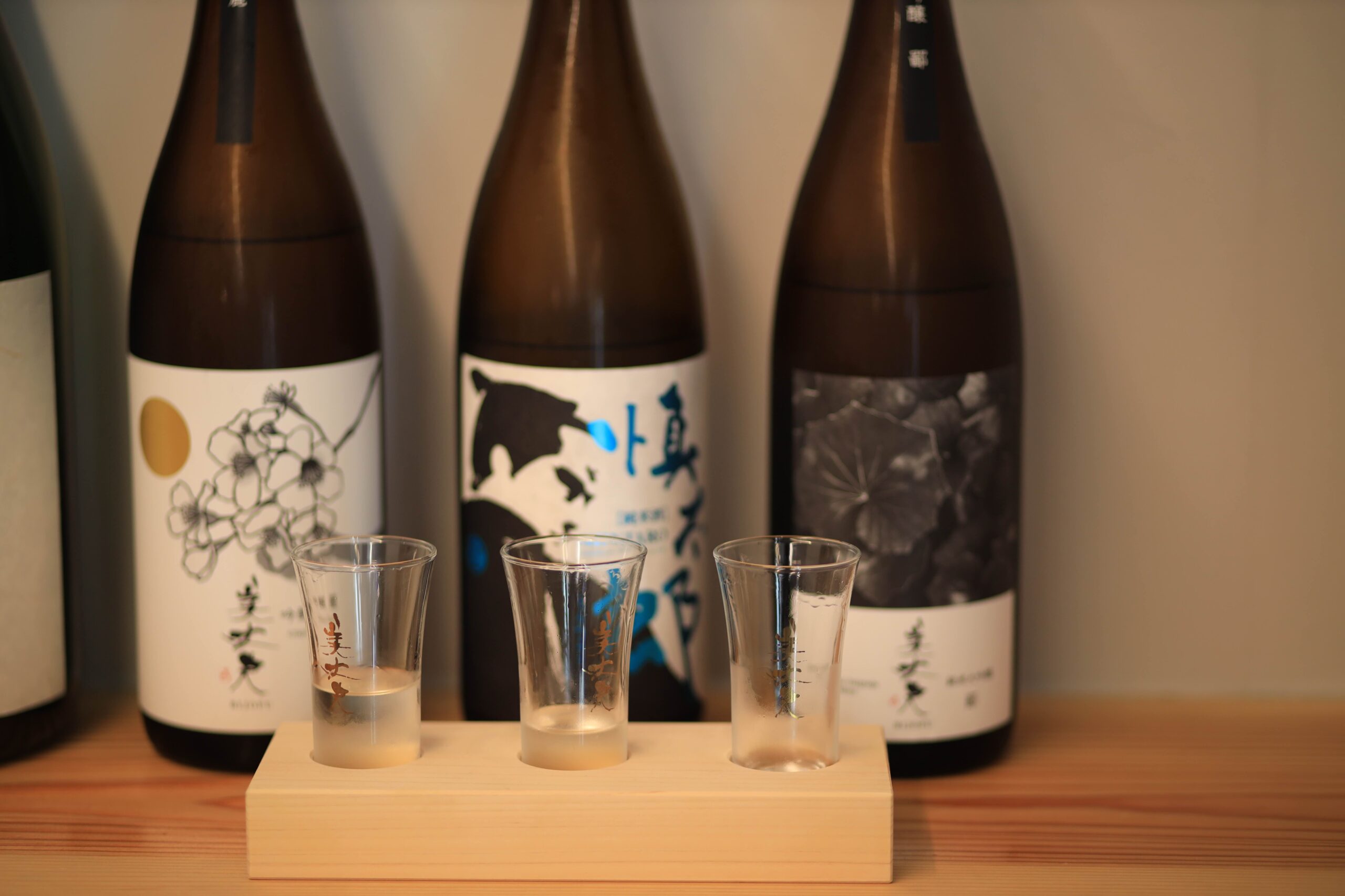 Three varieties of Kochi sake in tasting glasses with bottles at local sake shop