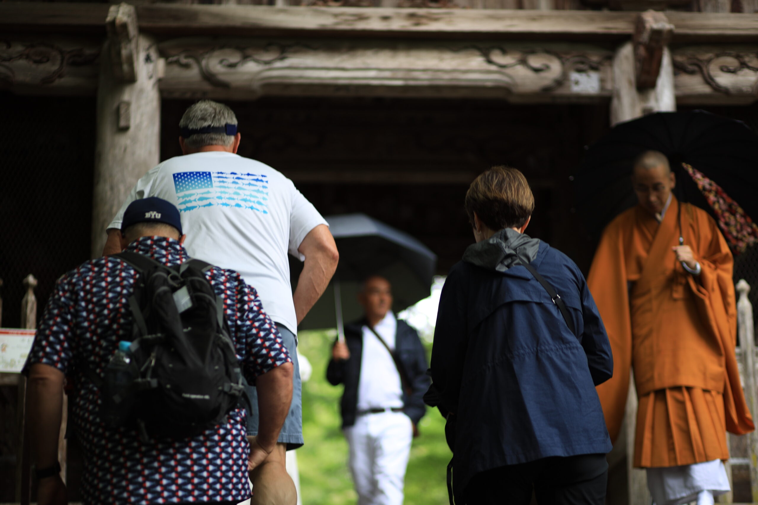 Tourists entering the historic gate of Chikurinji Temple in Kochi with monk in background