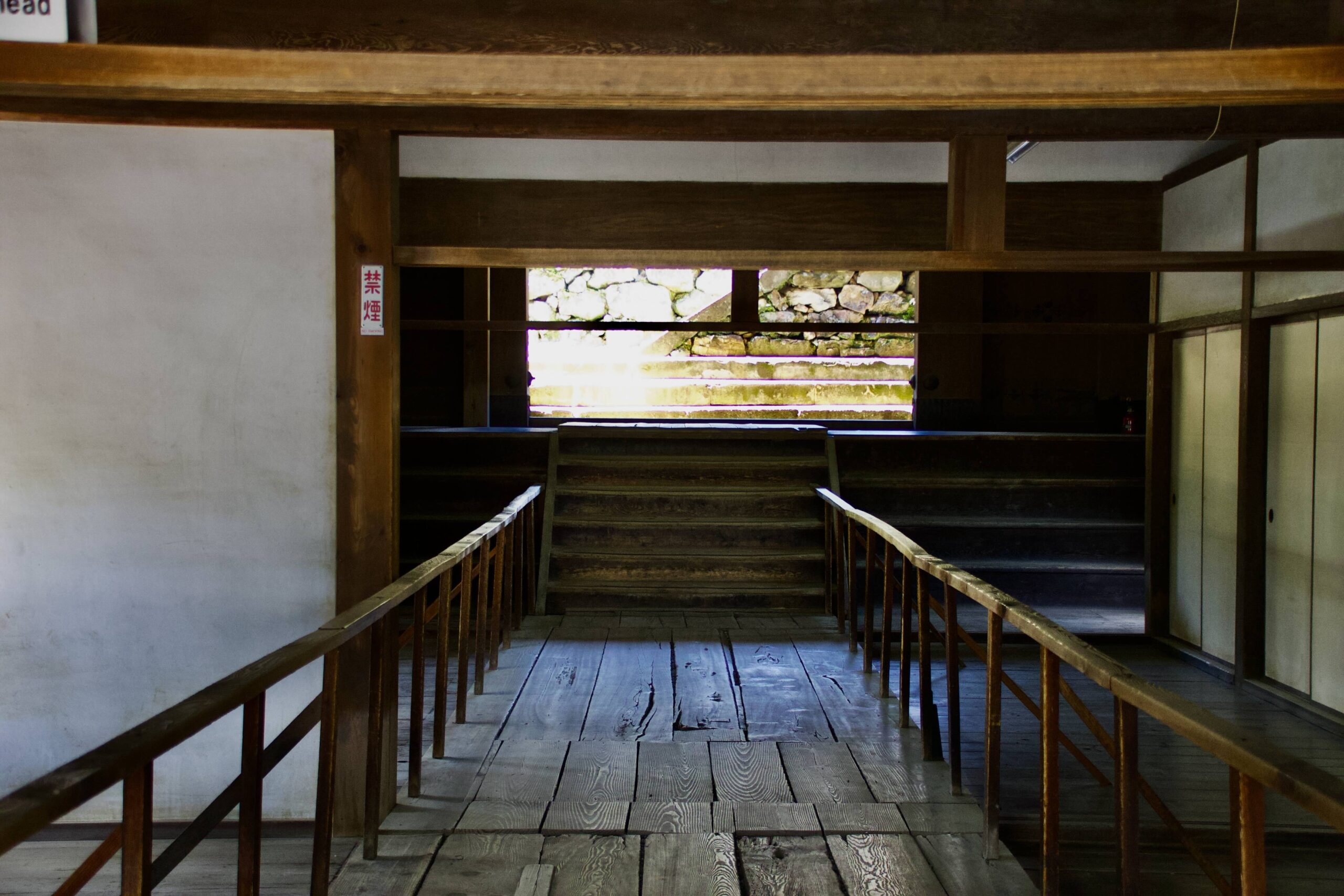 The original steep wooden staircases inside Kochi Castle keep — handrails are provided
