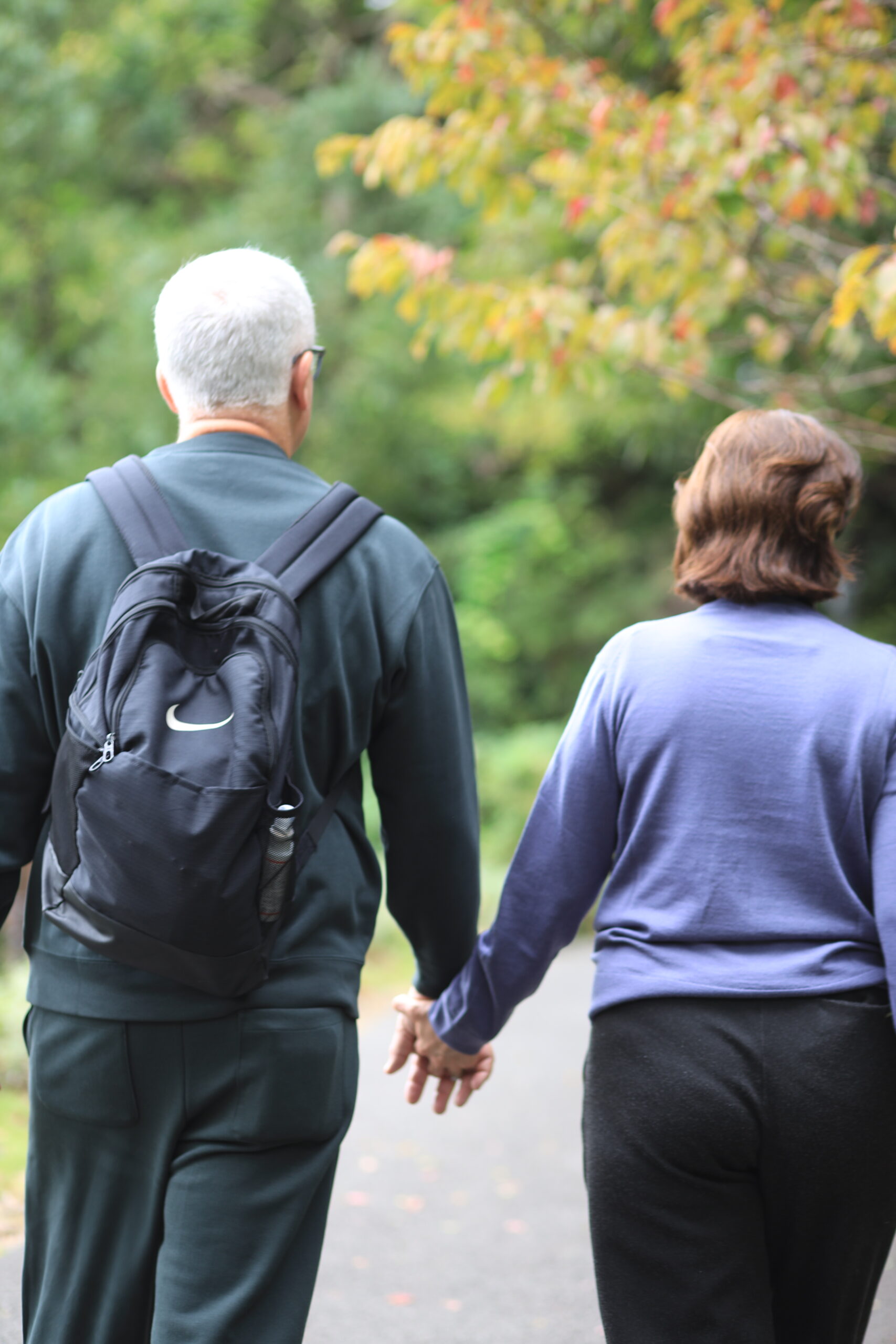 Couple walking hand in hand through autumn garden