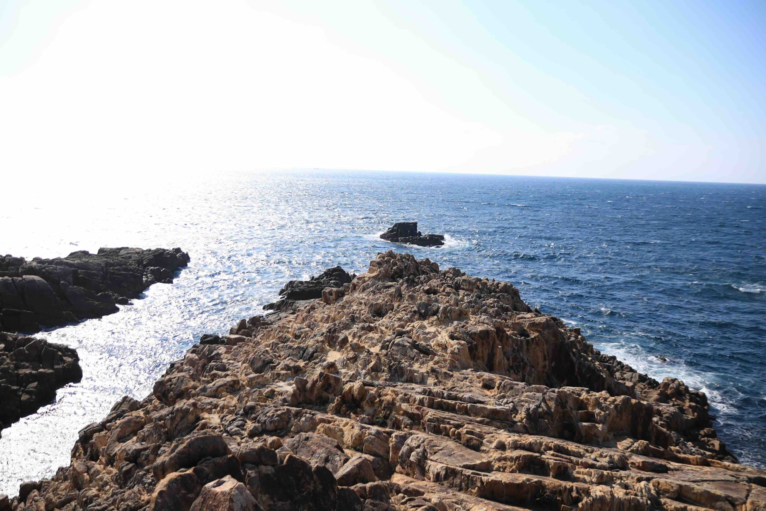 Small red shrine building with red torii gate against a blue sky at Ryugu Shrine