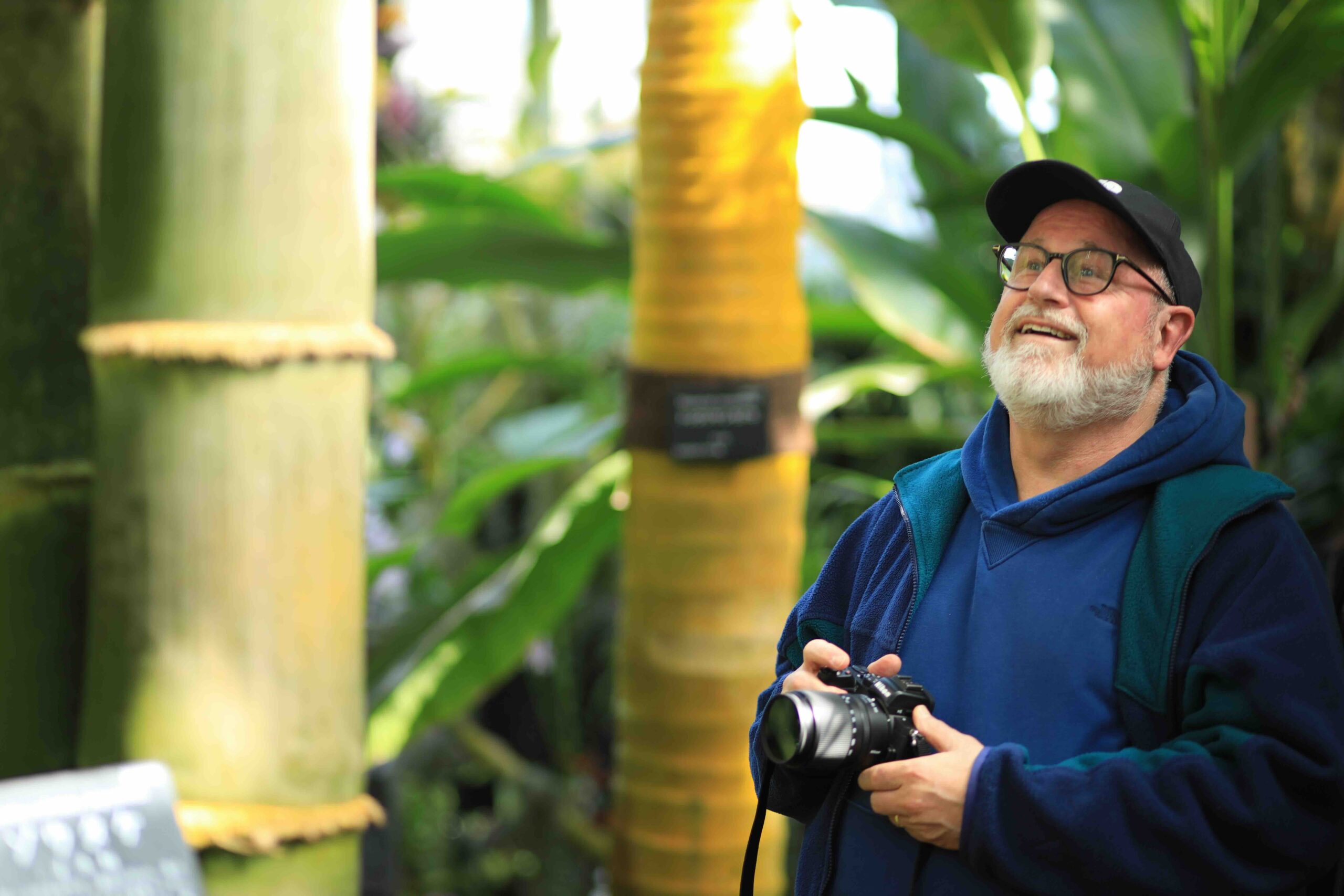 Guest with camera smiling in the tropical greenhouse at Makino Botanical Garden Kochi