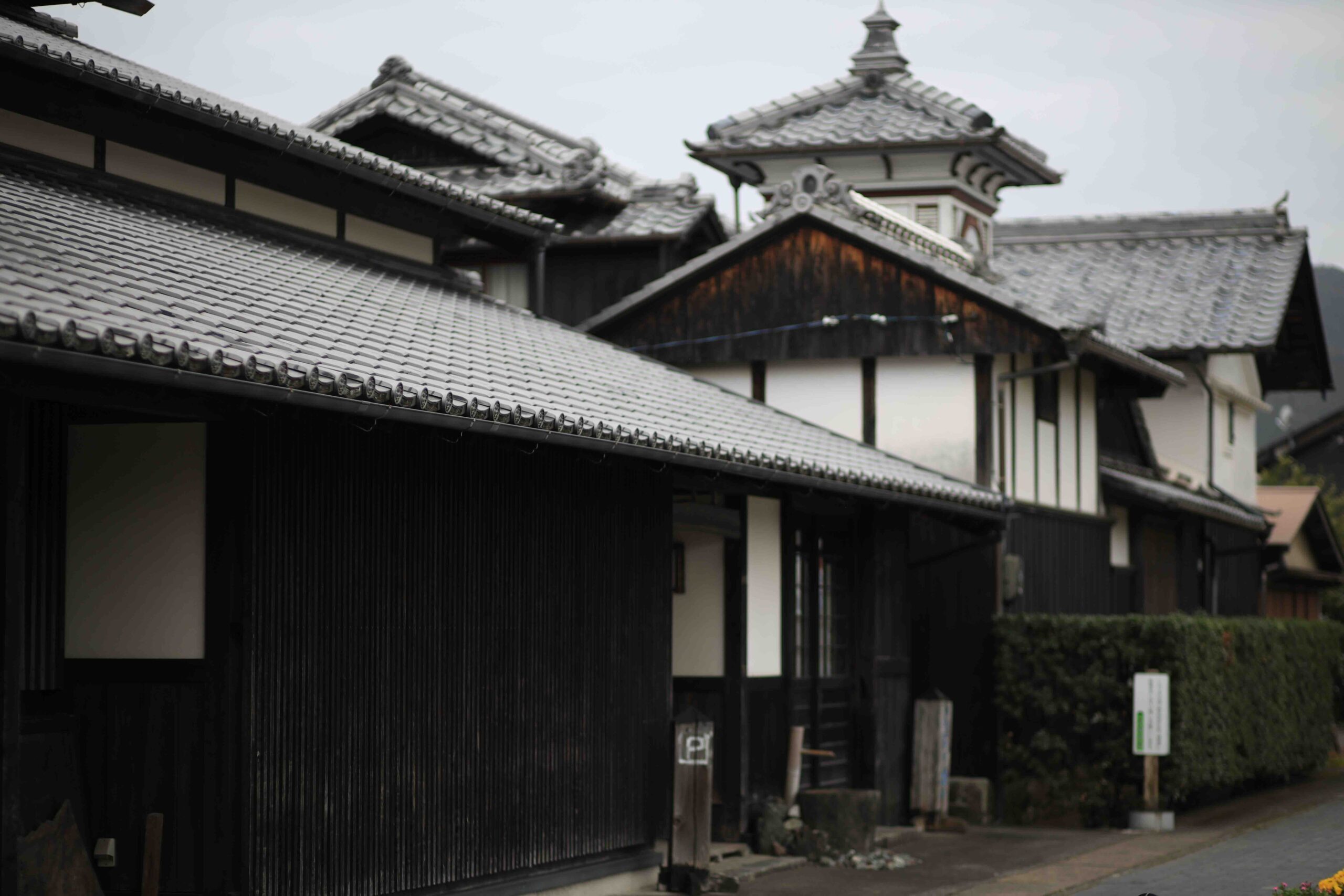 Traditional black-walled Edo-period buildings with the Aki City clock tower visible in the background
