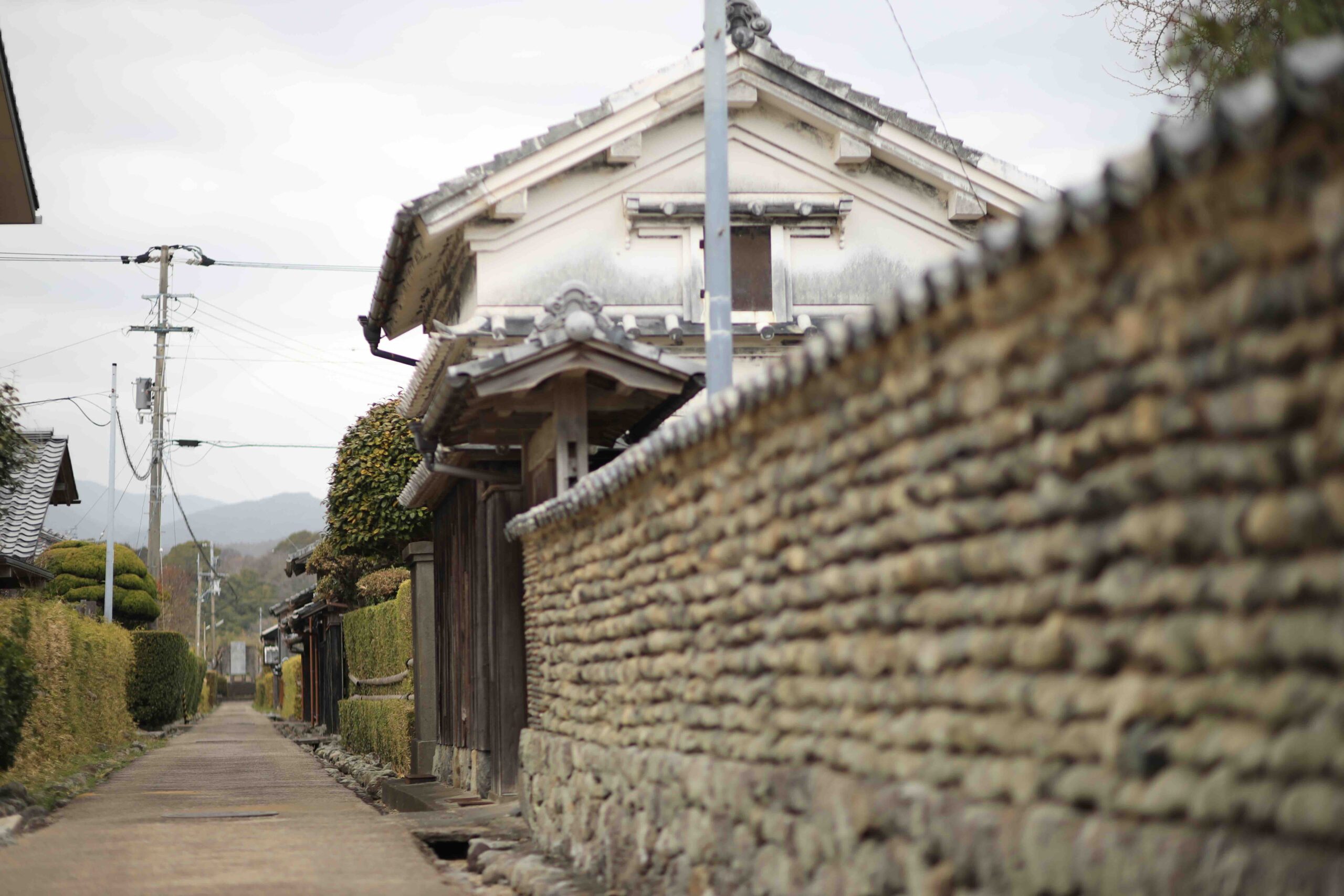 Stone wall and traditional earthen storehouse along a quiet street in Aki City historical district Kochi