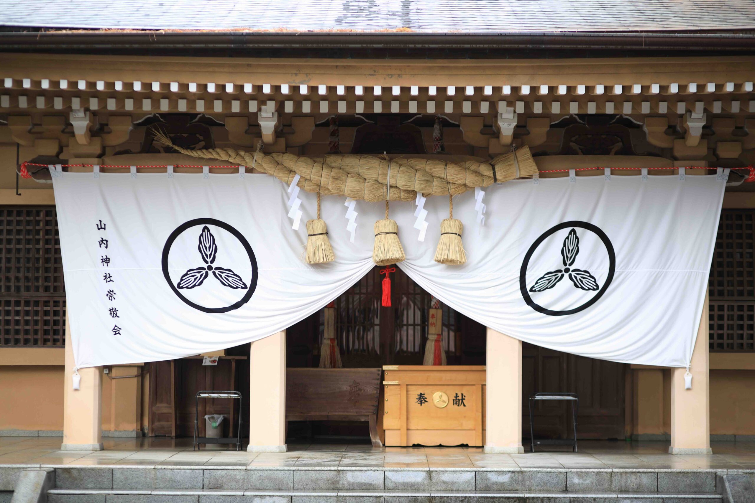Front view of Yamauchi Shrine main hall with white curtains and shimenawa rope
