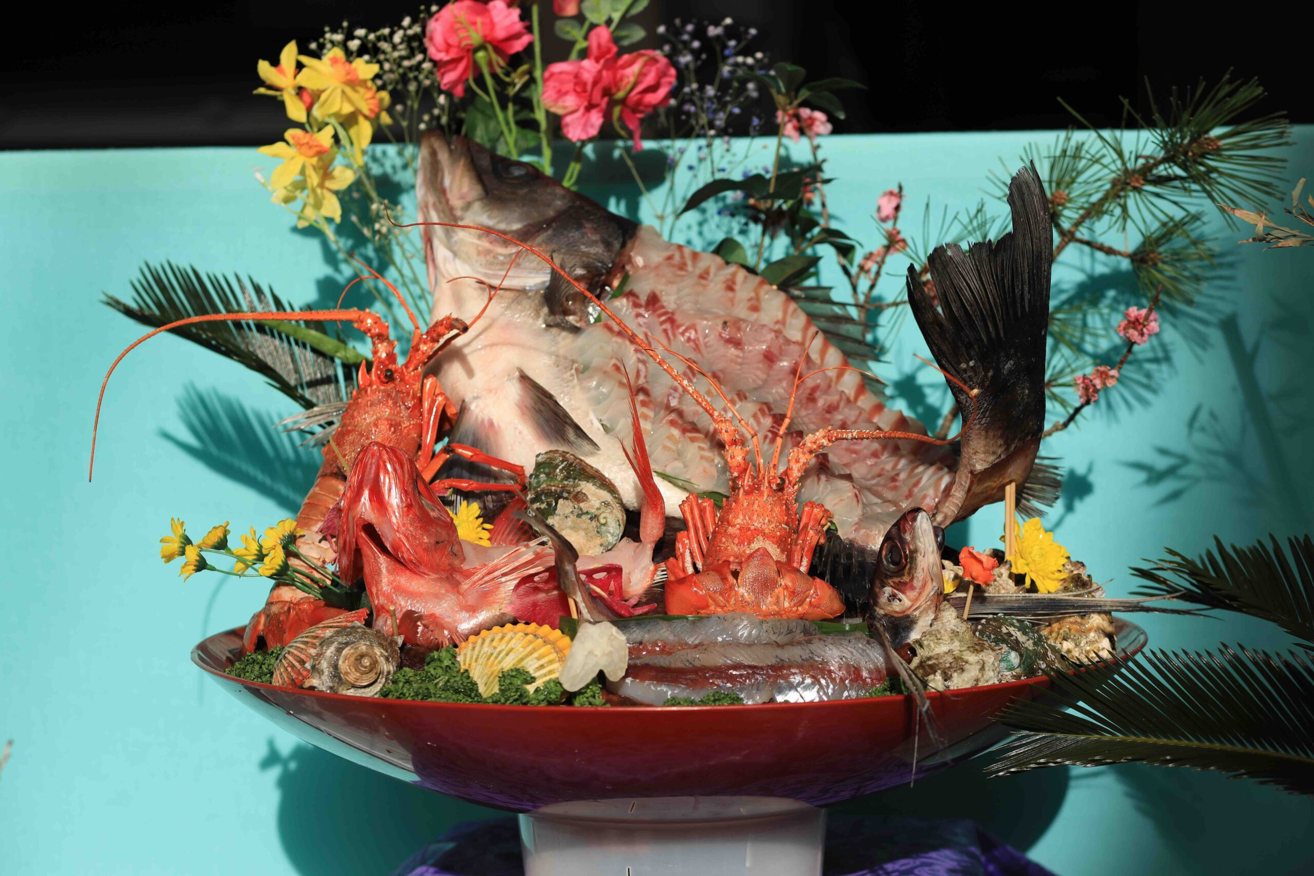 Sawachi platter with whole fish, lobsters, and abalone displayed with flowers at the festival