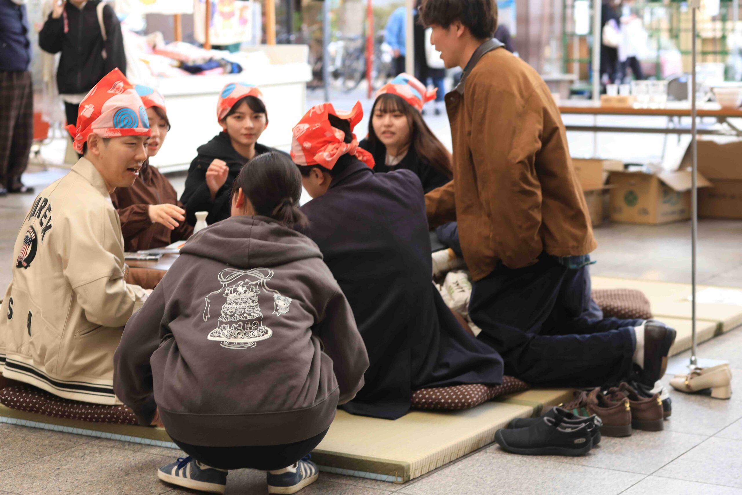 Young people playing traditional Kochi drinking games with red paper hats at Tosa no Okyaku