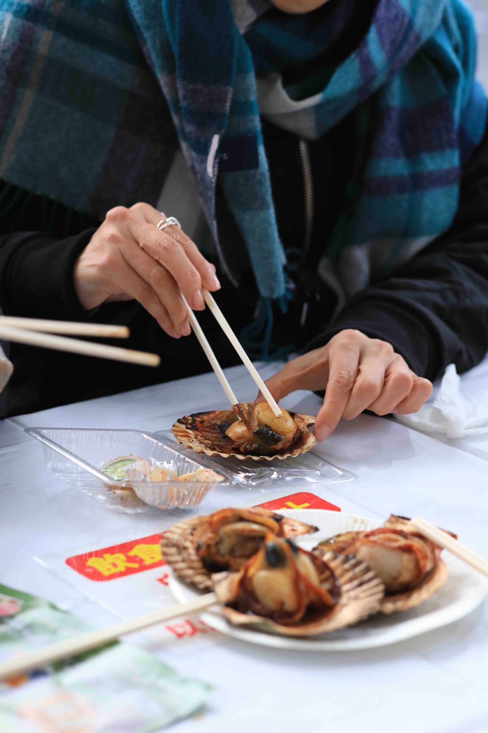 A person eating a freshly grilled Nagatarou scallop in the shell at the festival