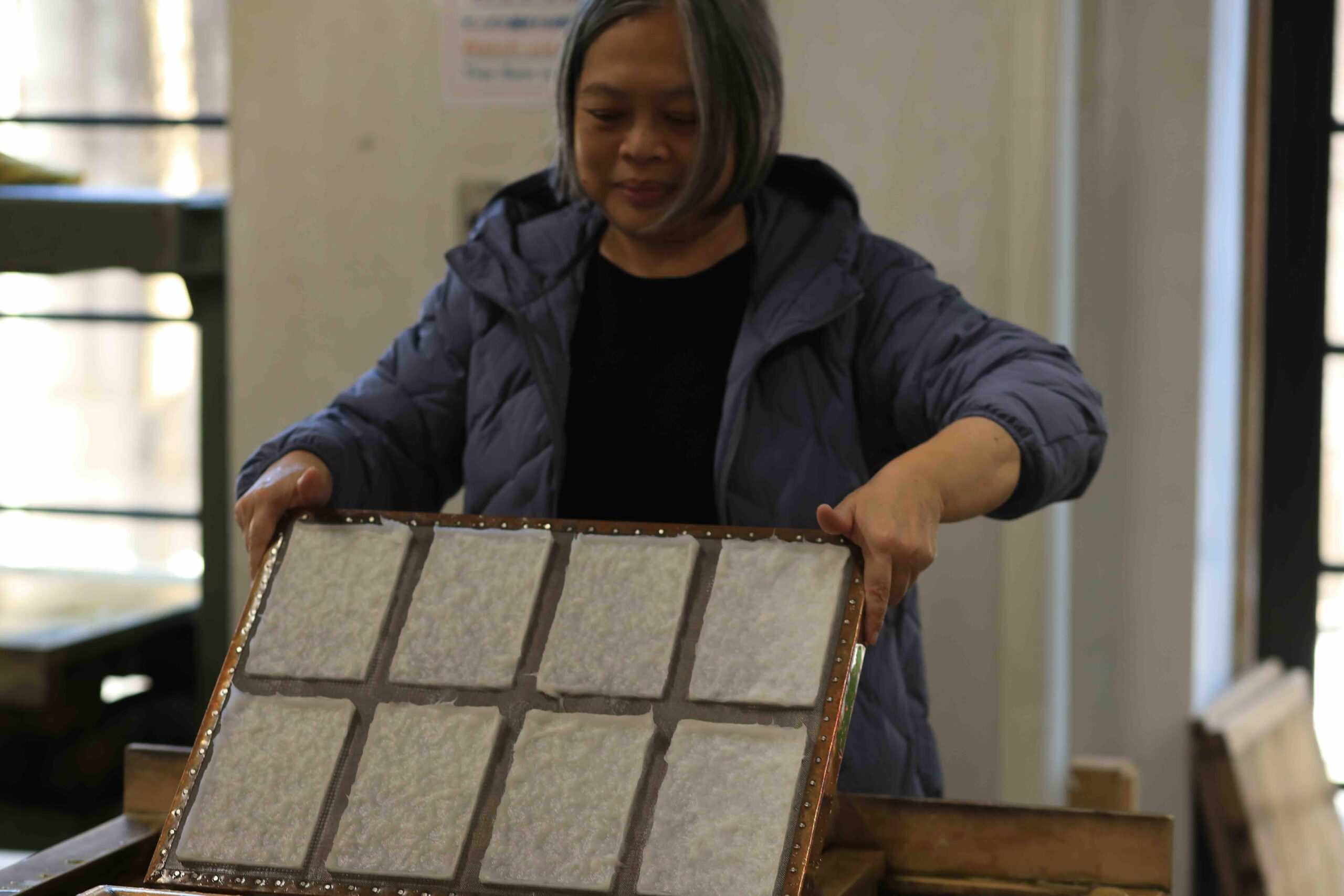 Guest holding freshly made washi paper sheets at the Paper Museum in Kochi