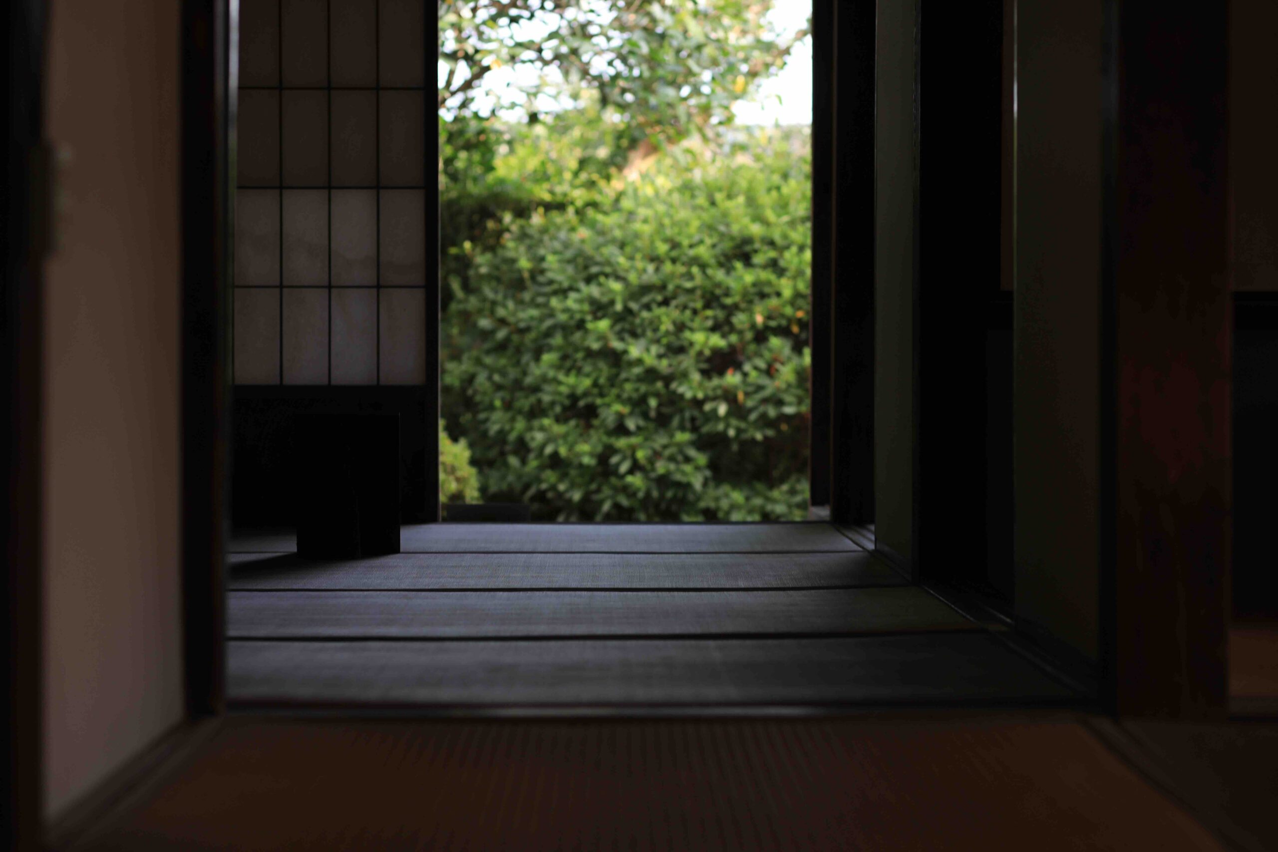View from inside a traditional tatami room through shoji screens to a lush green garden in an Aki samurai residence
