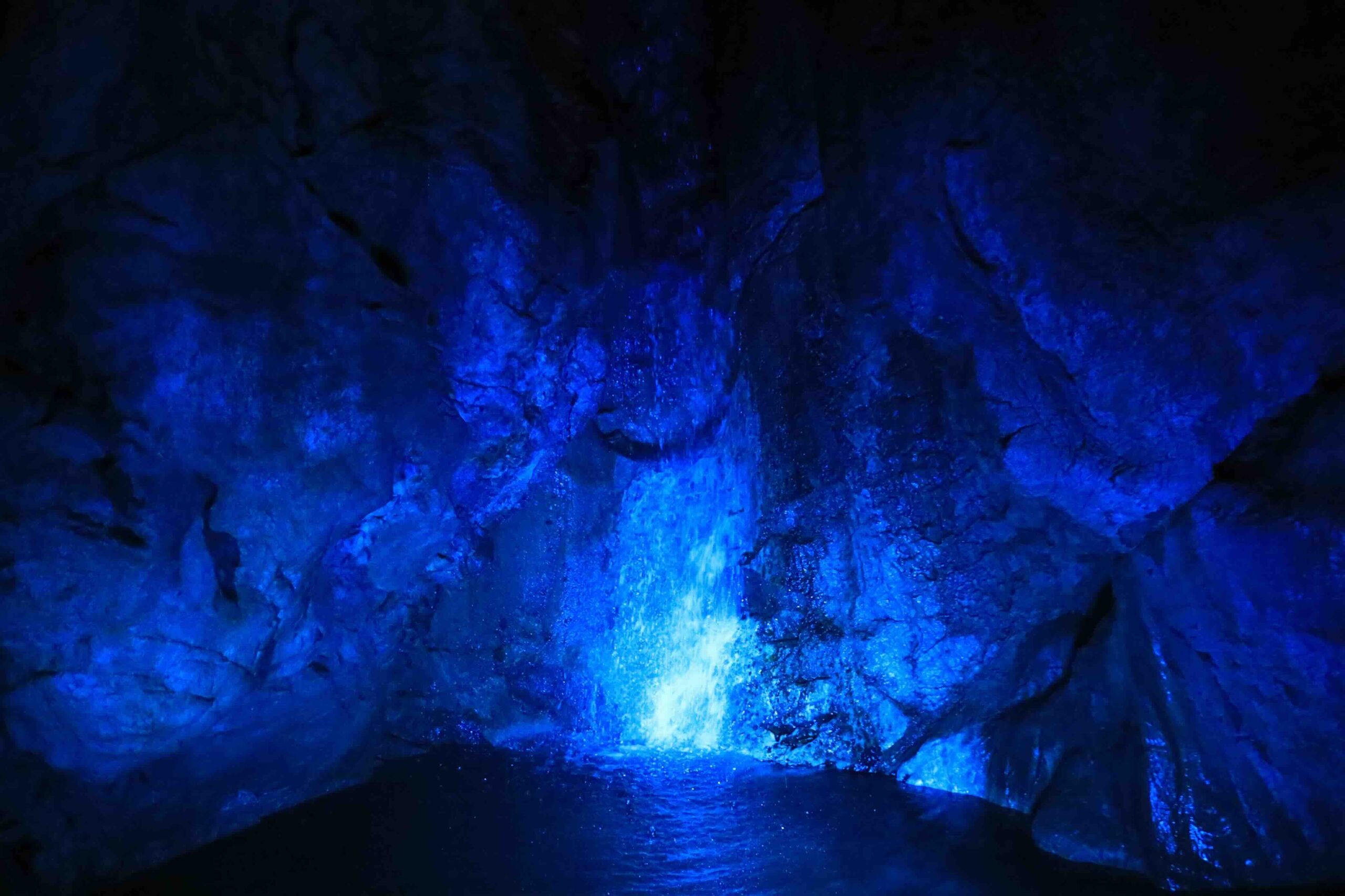 Underground waterfall illuminated in dramatic blue light inside Ryugado cave Kochi