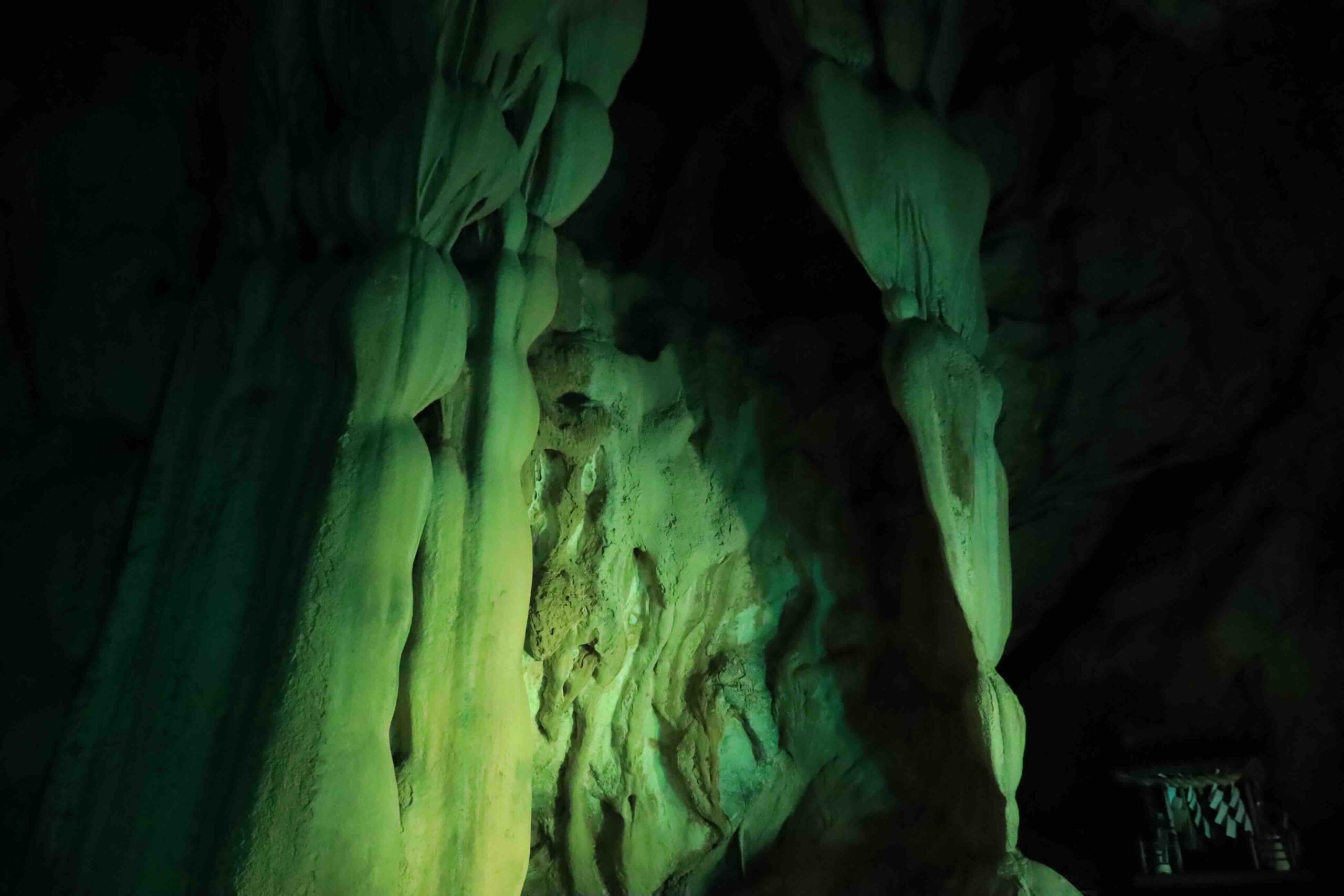 Large stalactite formation glowing in green light inside Ryugado cave Kami City Kochi