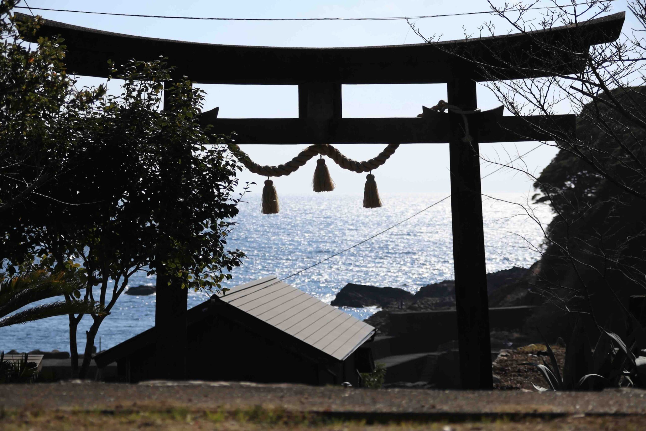 Silhouette of torii gate with the Pacific Ocean shining in the background at Ryugu Shrine