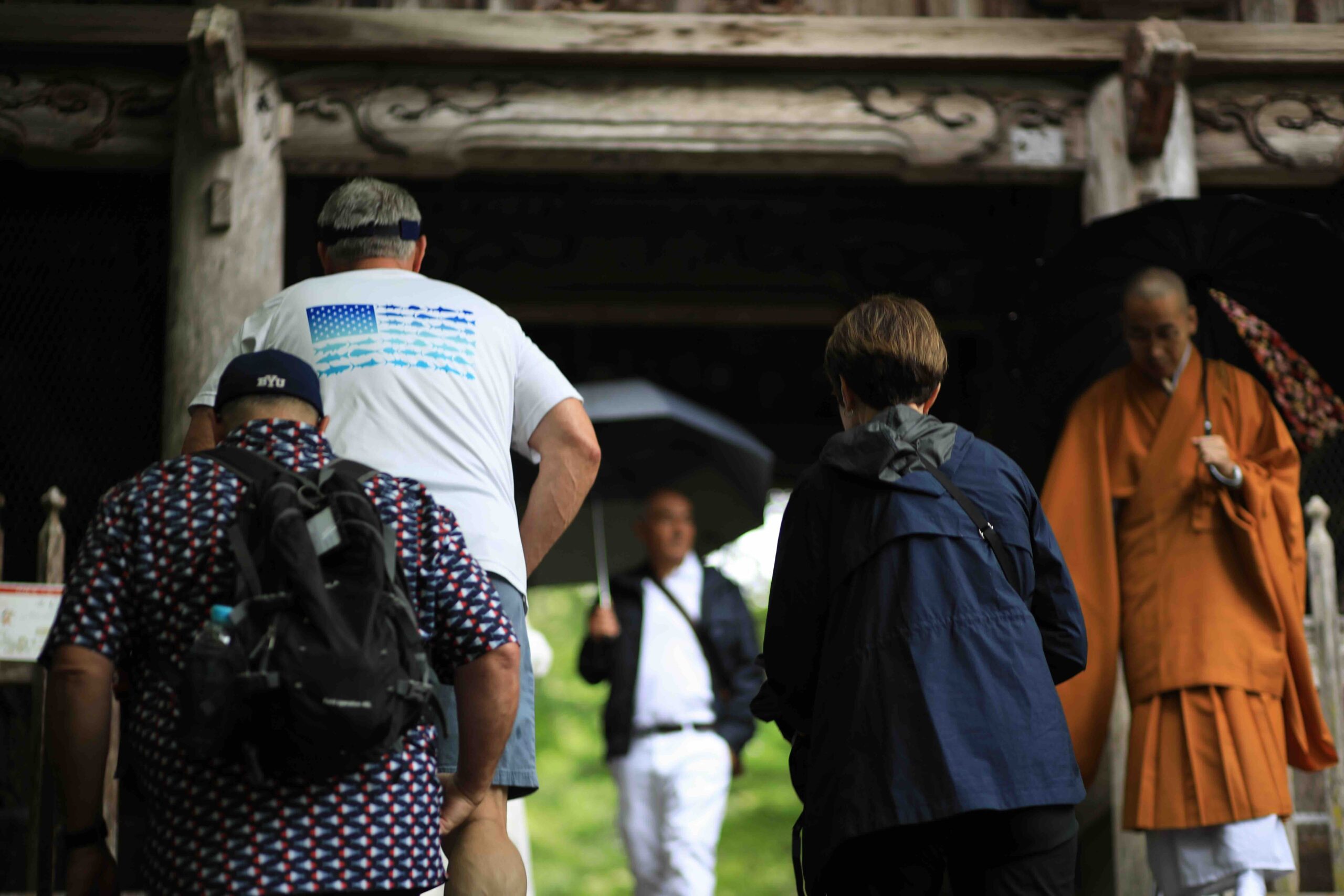 Cruise ship guests walking toward a Buddhist monk at the entrance of Chikurinji Temple