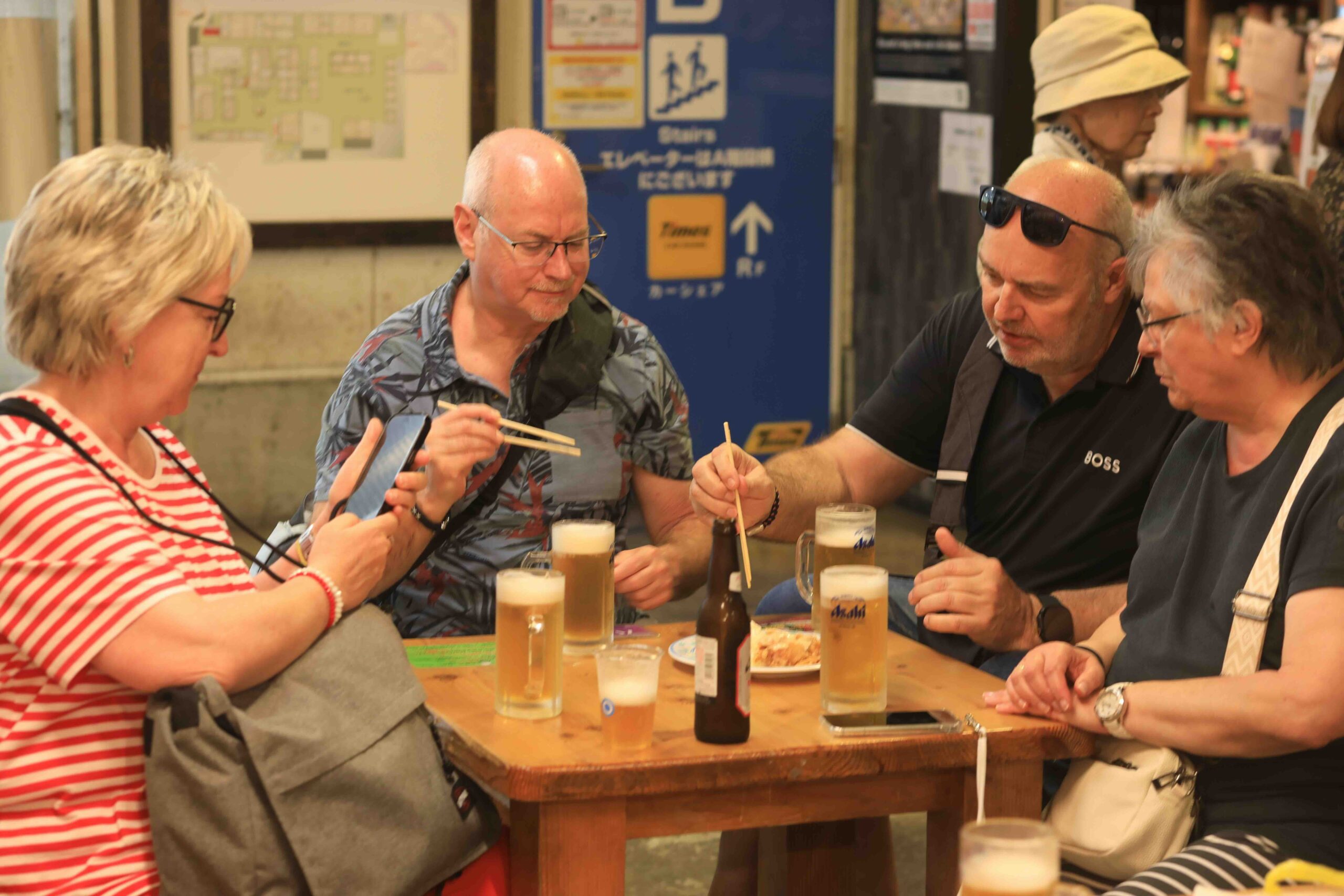 Guests enjoying food and cold beer at a shared table inside Hirome Market