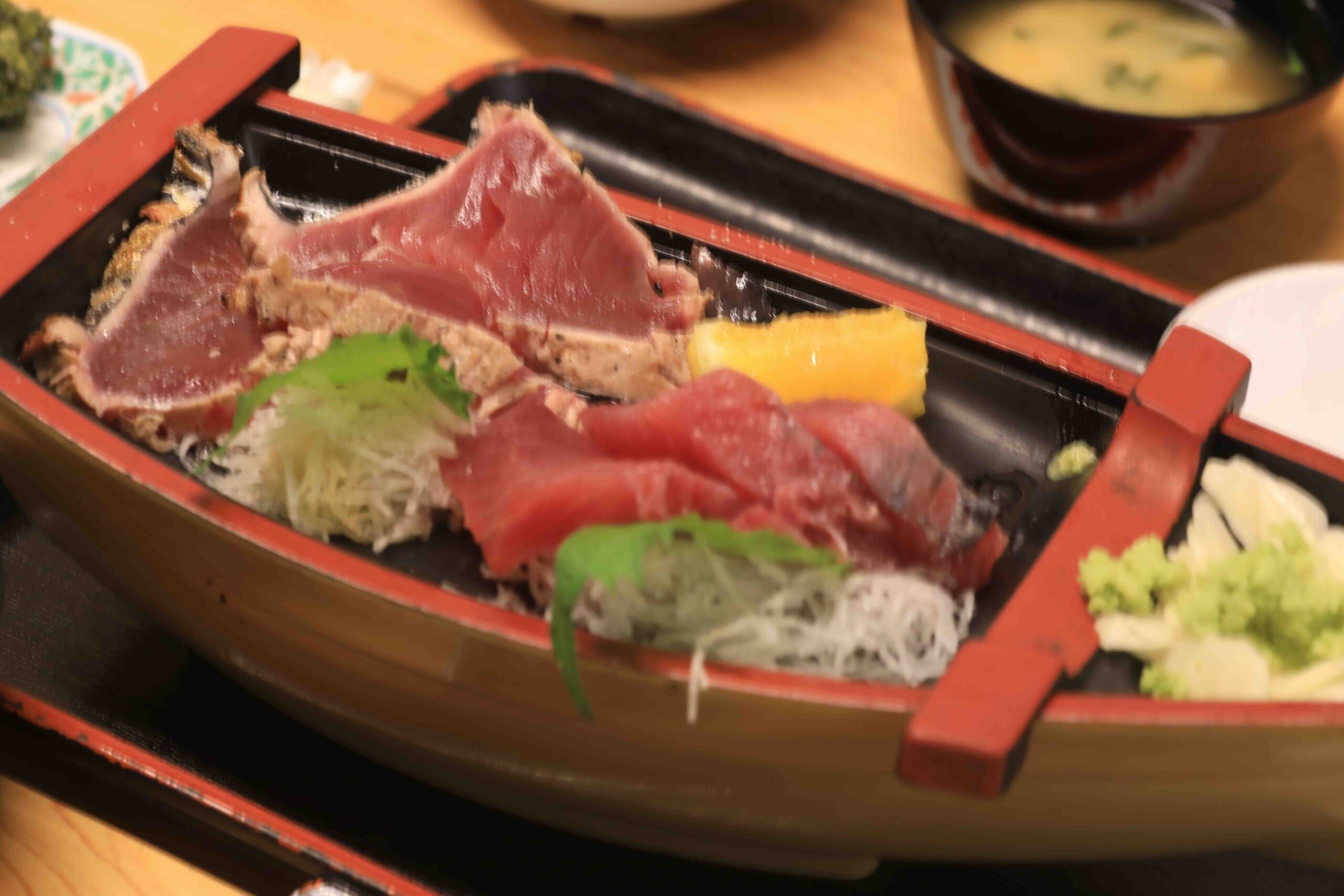 Katsuo no tataki seared bonito served in a traditional boat-shaped dish at Hirome Market