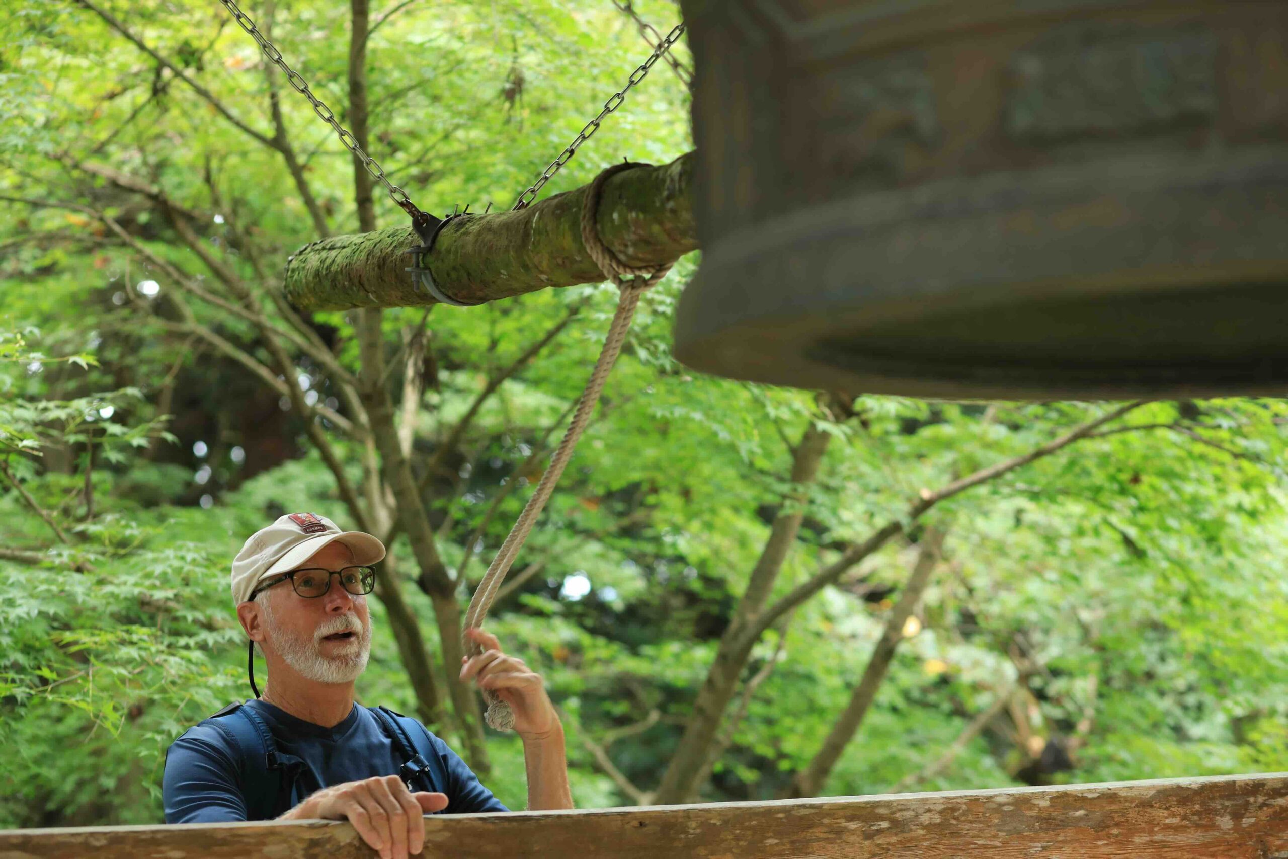 A visitor ringing the large bronze temple bell at Chikurinji Temple before praying
