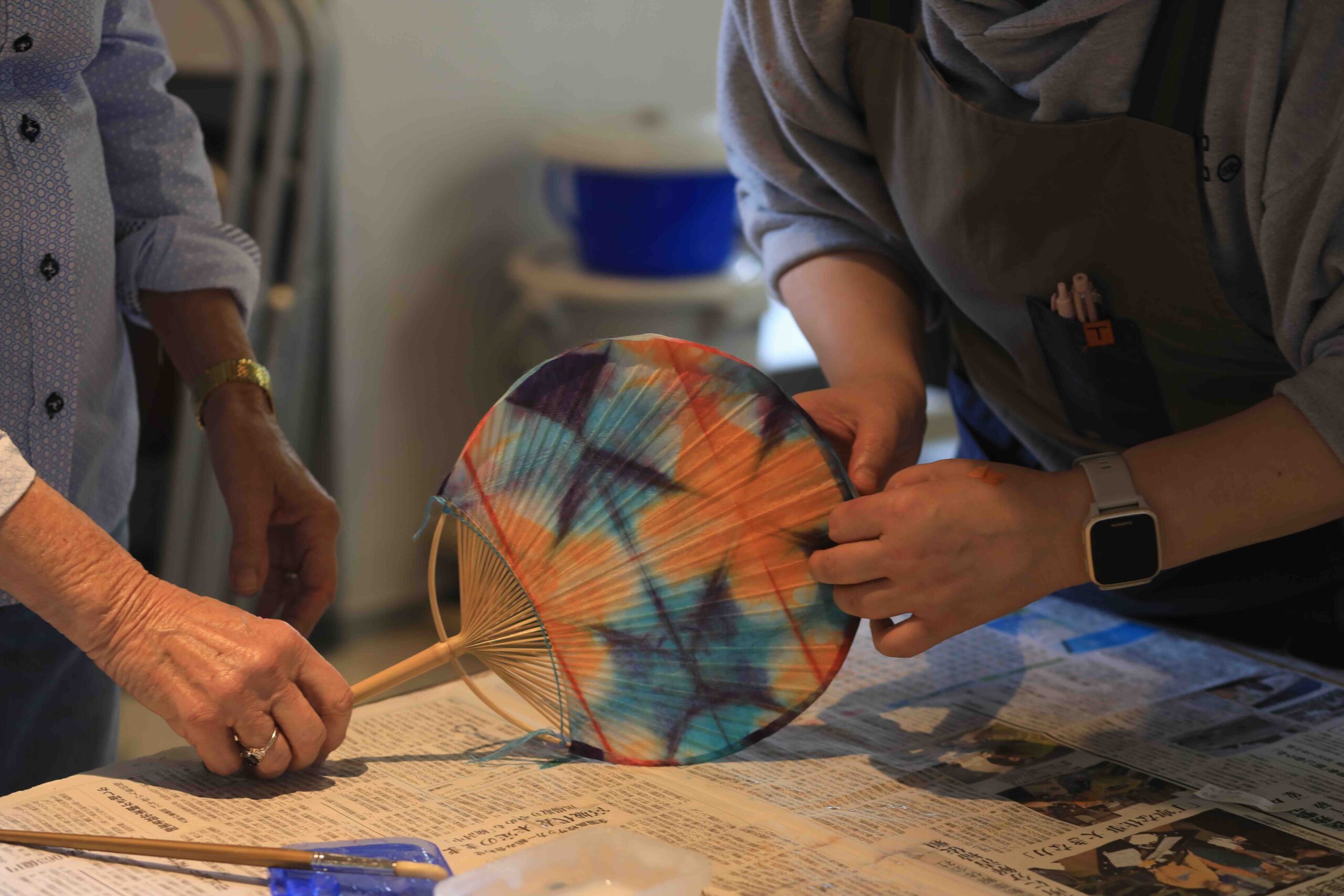 Guests from Australia carefully folding washi paper at the beginning of the uchiwa fan-making experience at Kuraud in Ino Town, Kochi